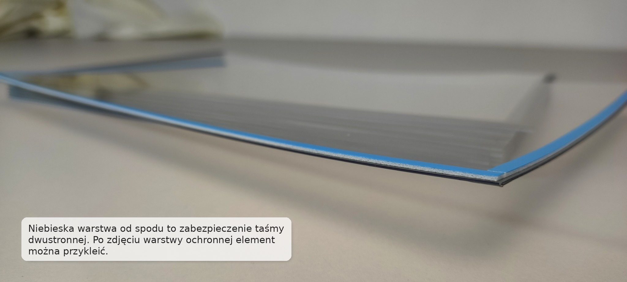 Zbliżenie na taśmę montażową od spodu szarej kieszeni samoprzylepnej na dokumenty